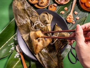 Zongzi, woman eating steamed rice dumplings on green table background, food in dragon boat festival duanwu concept, close up, copy space, top view, flat lay