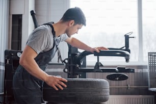 Colocar el elemento dentro del neumático. Un joven trabaja con discos de ruedas en el taller durante el día.