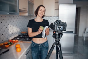 Simplemente posando para la cámara y haciendo algo de comida con frutas. Chica en la cocina moderna de casa en su fin de semana por la mañana.