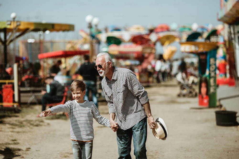 Nonno e nipote che si divertono e trascorrono del tempo di buona qualità insieme nel parco divertimenti.