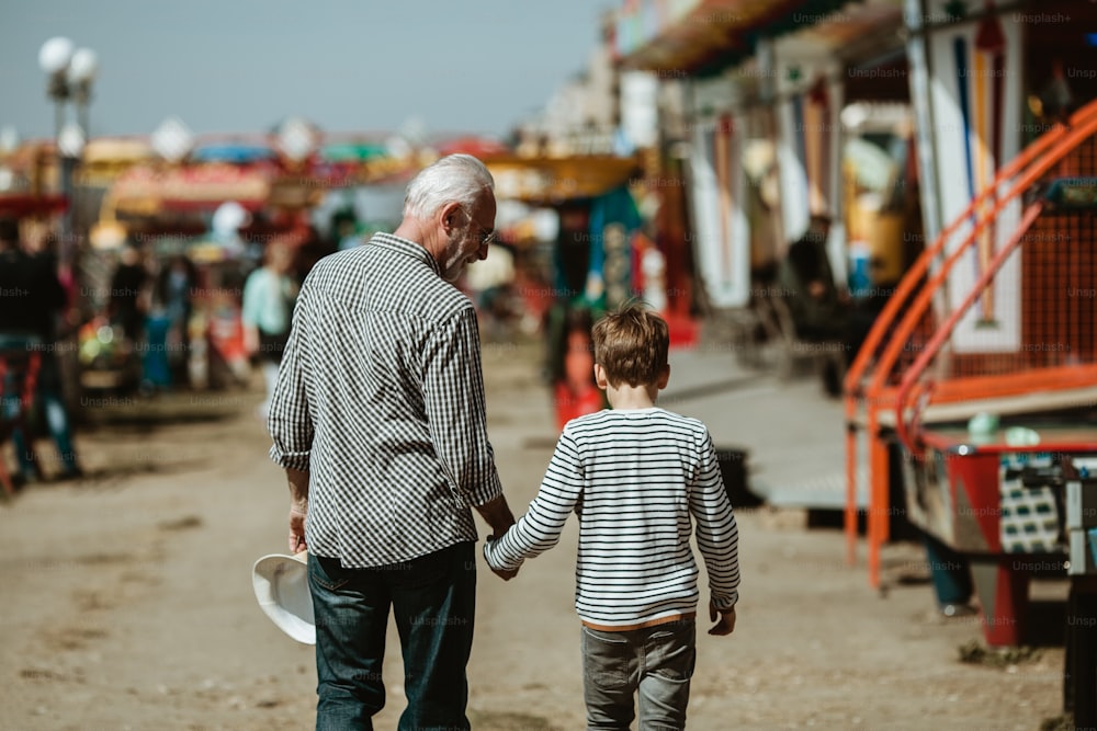 Grandfather and grandson having fun and spending good quality time together in amusement park.