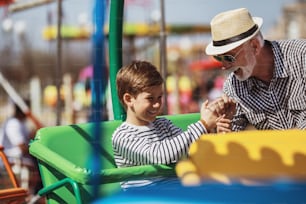 Abuelo y nieto divirtiéndose y pasando tiempo de buena calidad juntos en el parque de atracciones.