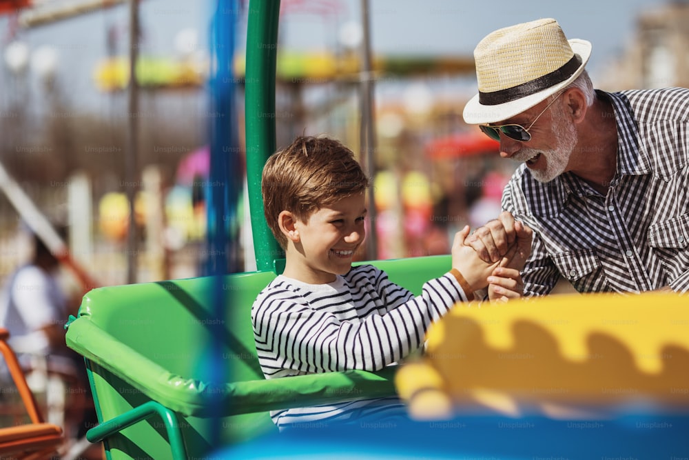 Grandfather and grandson having fun and spending good quality time together in amusement park.