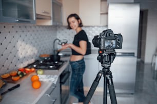 Focus on the camera. Girl in the modern kitchen at home at her weekend time in the morning.