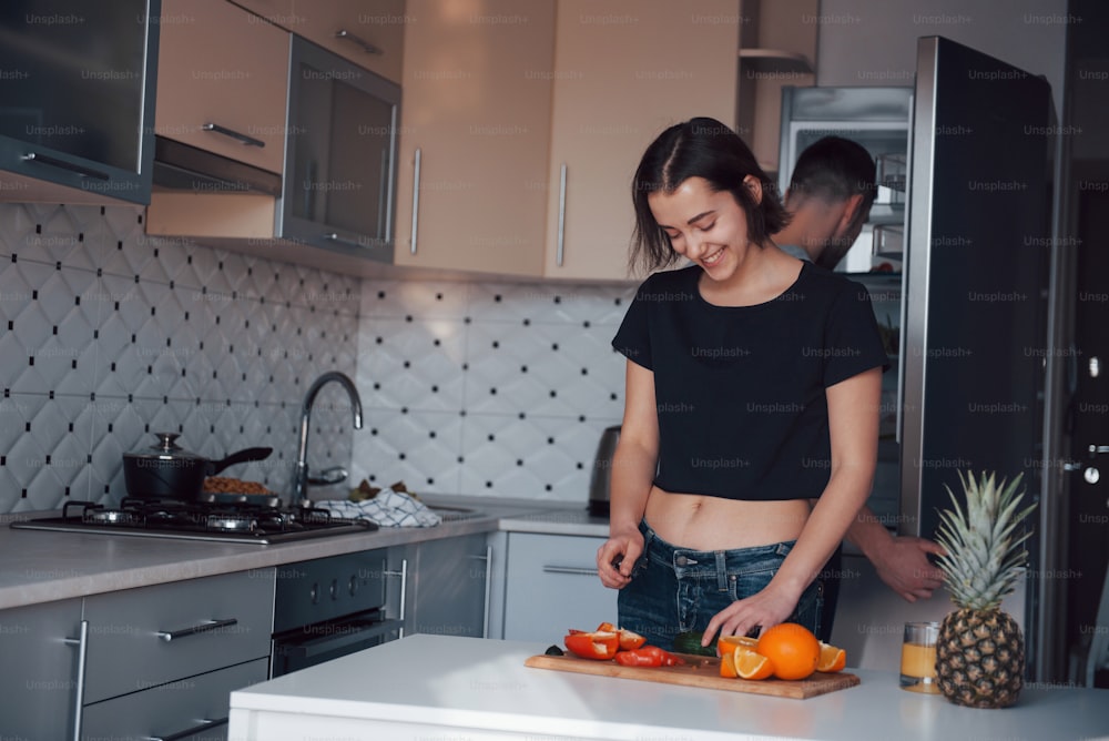 Opening the refrigerator. Young couple in the modern kitchen at home at their weekend time in the morning.
