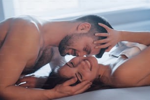 Laughing together. Sexy couple lying on the bed and enjoying themselves at morning time.