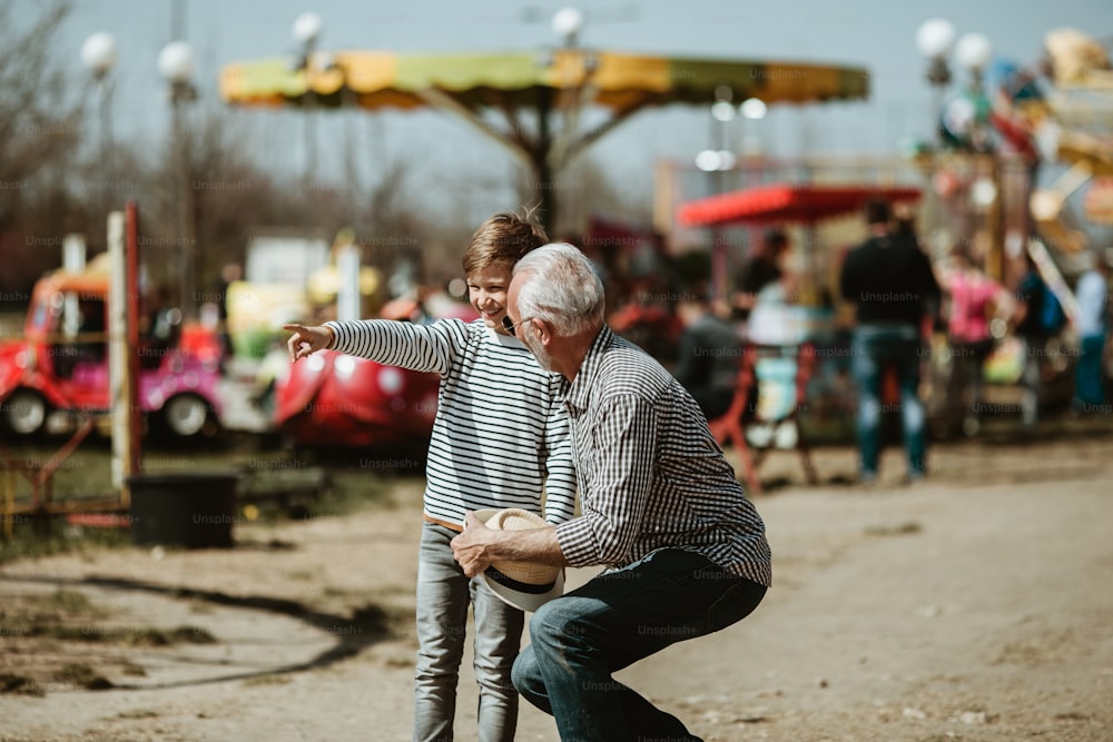 Grand-père et petit-fils s’amusent et passent du temps de qualité ensemble dans le parc d’attractions.