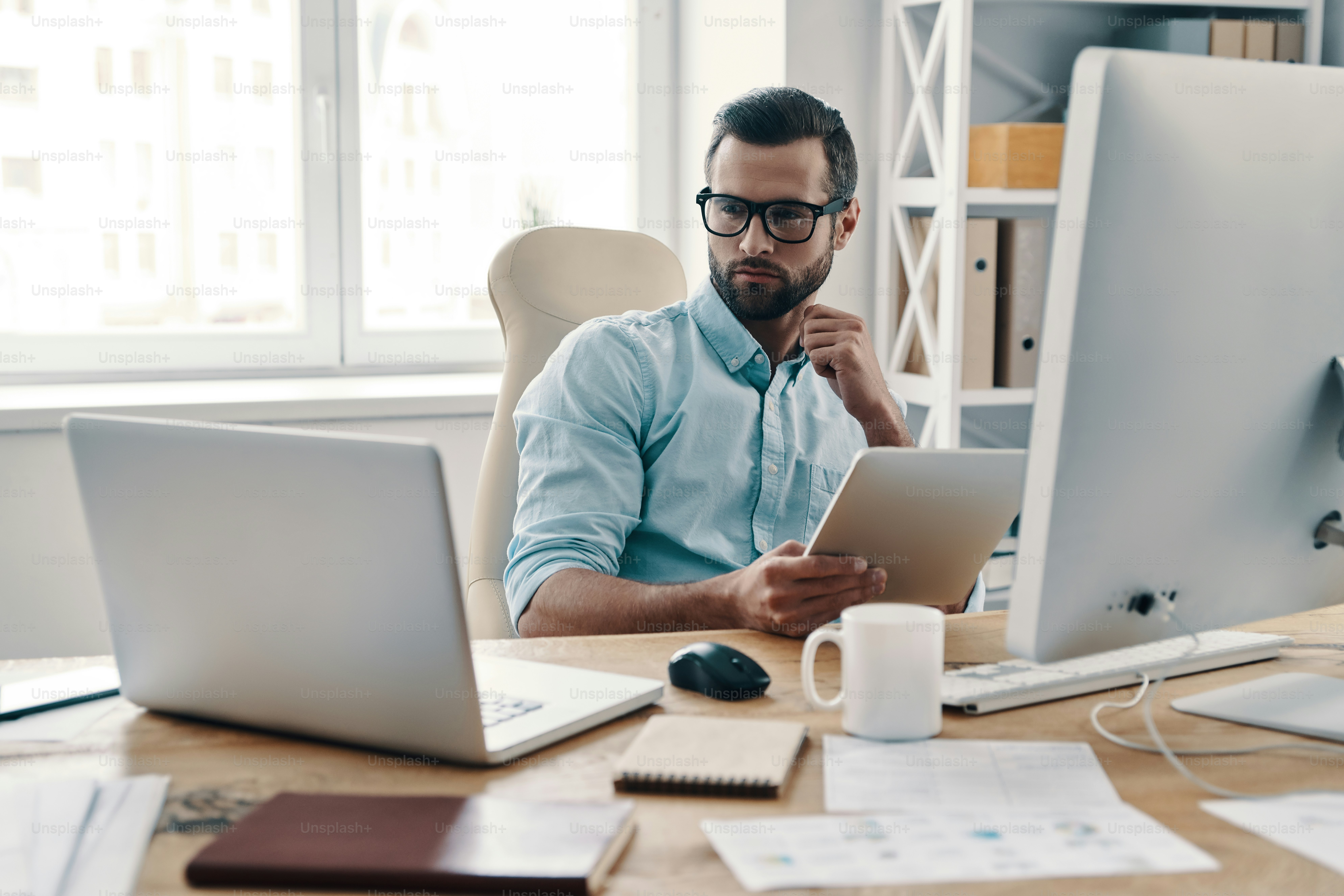 Young modern businessman working using digital tablet while sitting in the office