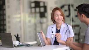 Asian female doctor using tablet computer and talking to male Asian patient