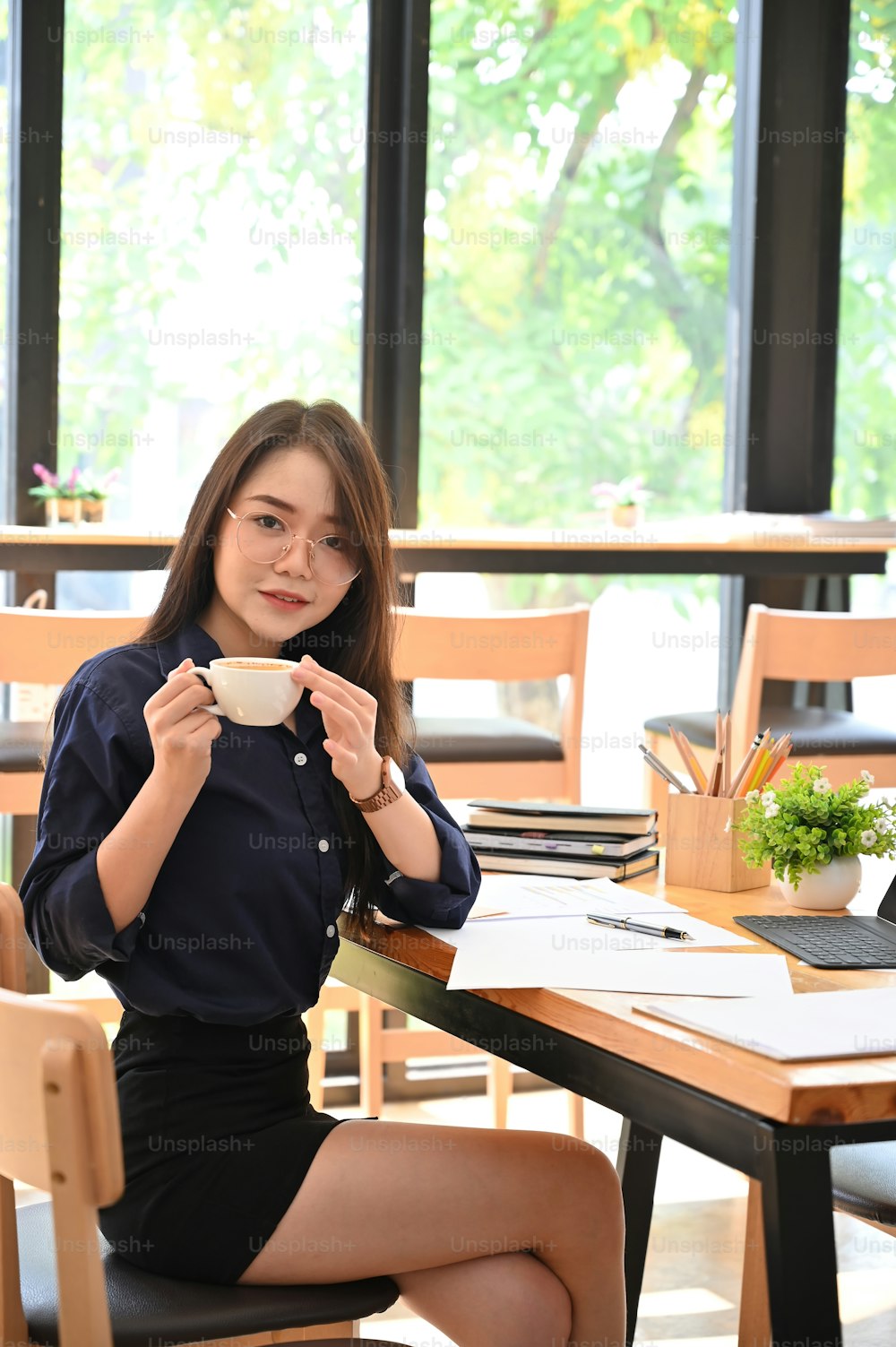 Woman working in co working space with coffee cup on hands.