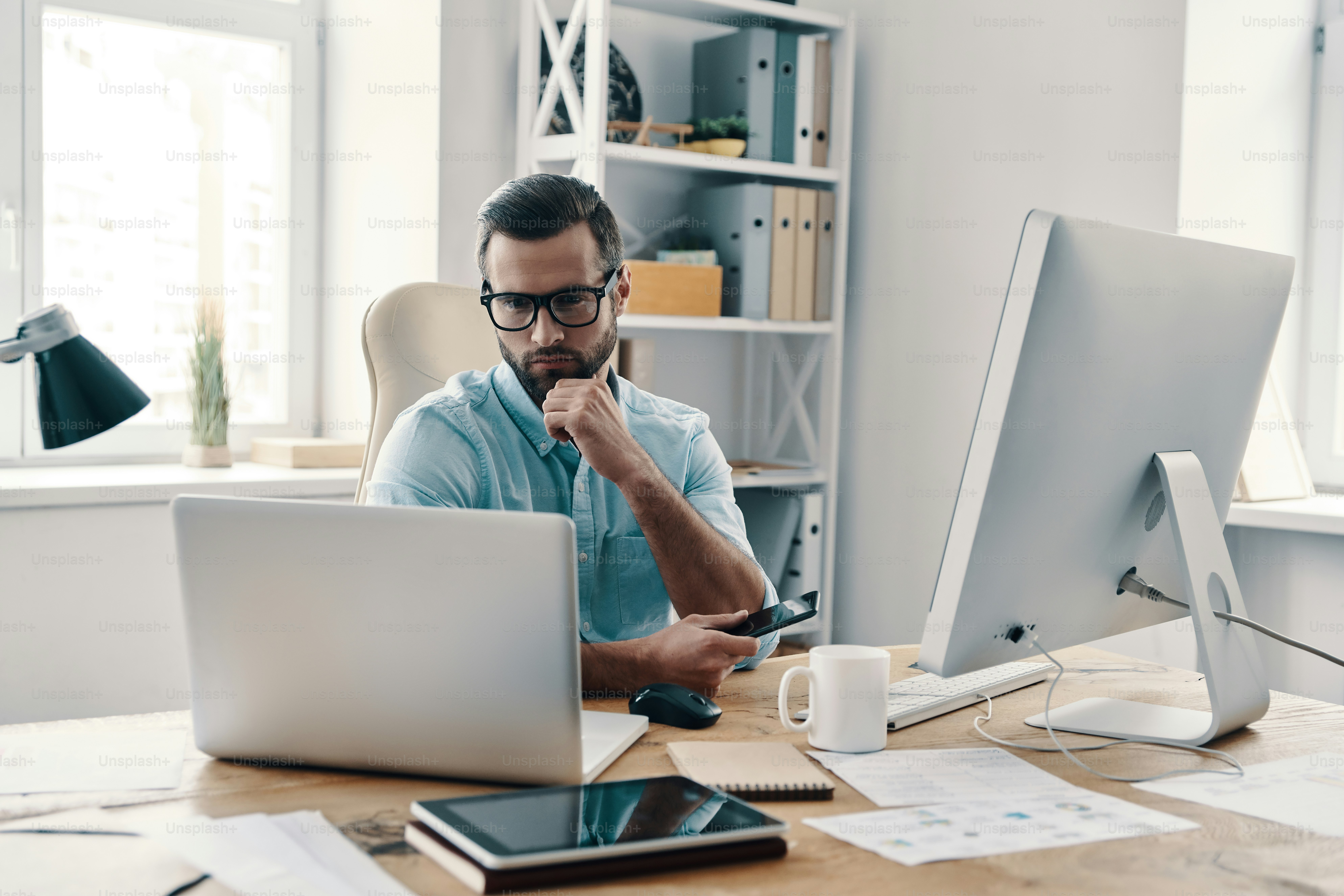 Young modern businessman working using computer while sitting in the office