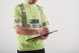 Close up view. Policeman in green uniform stands against white background in the studio.