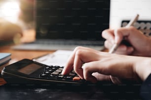 donna d'affari che utilizza una calcolatrice e un computer portatile per calcolare i numeri dal rapporto finanziario, concetto di contabilità finanziaria