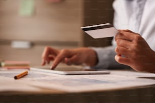 Close up de empresária com cartão de crédito verificando sua conta bancária no tablet digital.