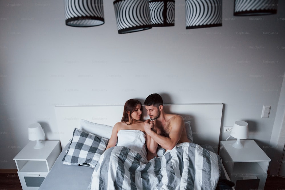 손에 키스. 섹시한 커플은 침대에 누워 아침 시간에 즐거운 시간을 보내고 있다.