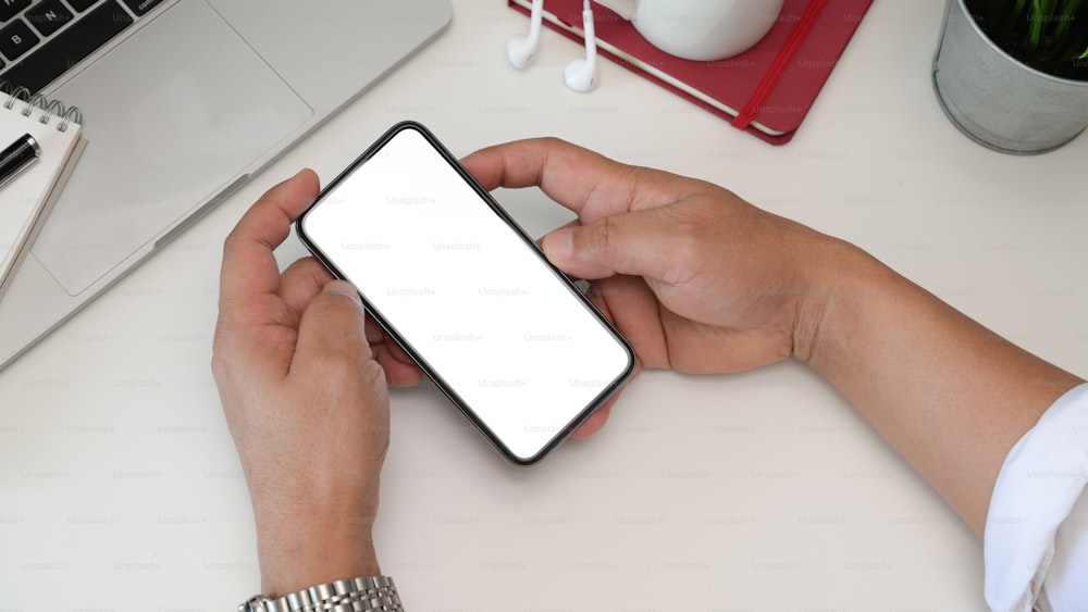Top view man hands holding blank screen mobile smartphone on workspace
