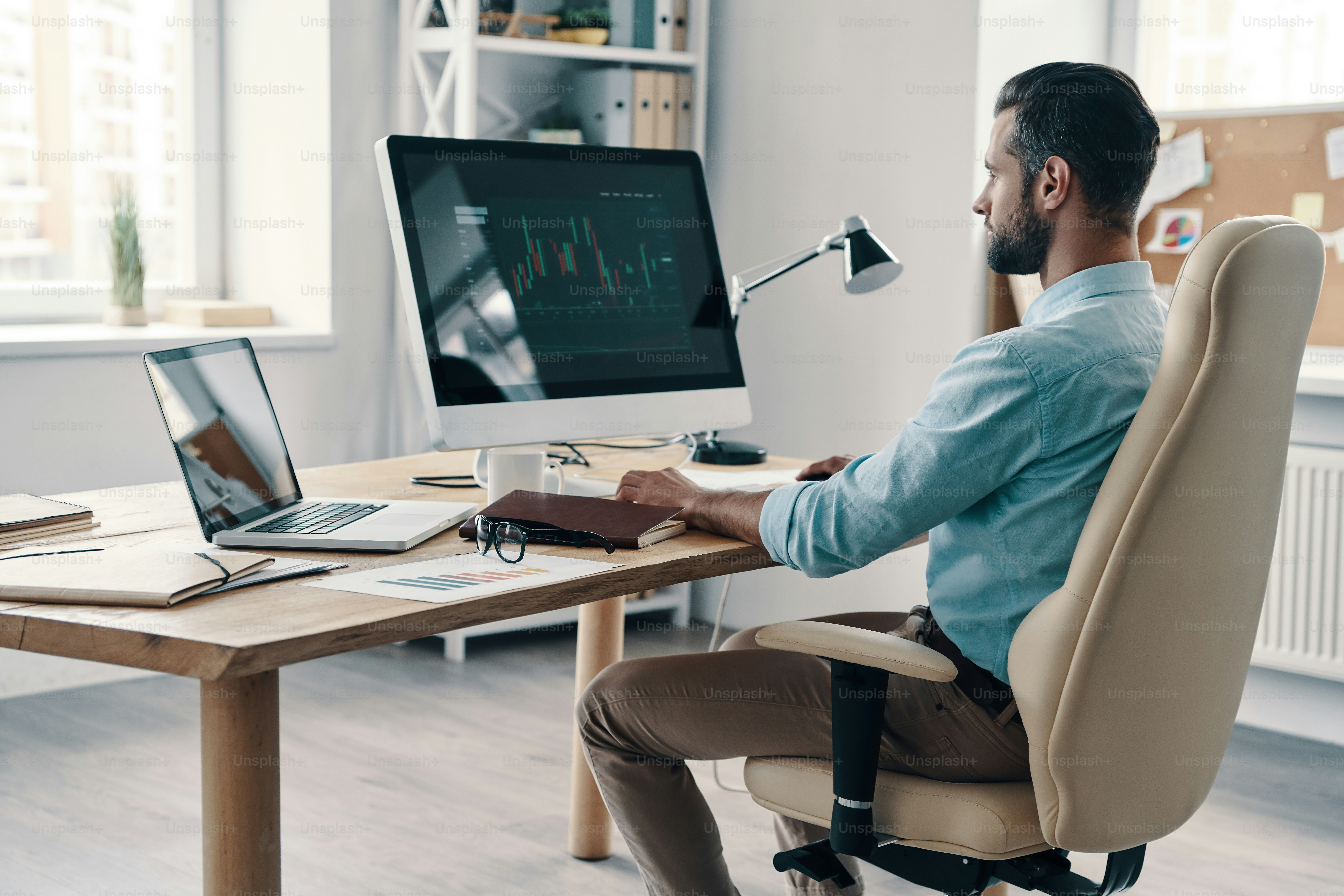 Young modern businessman analyzing data using computer while sitting in the office