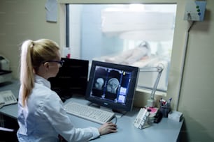 Radiologe analysiert Gehirn-MRT-Scan-Ergebnisse eines Patienten auf Computermonitor im Kontrollraum.