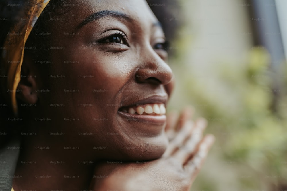 Foto recortada de uma jovem americana aproveitando o tempo enquanto sorri para alguém. Foco no rosto feminino