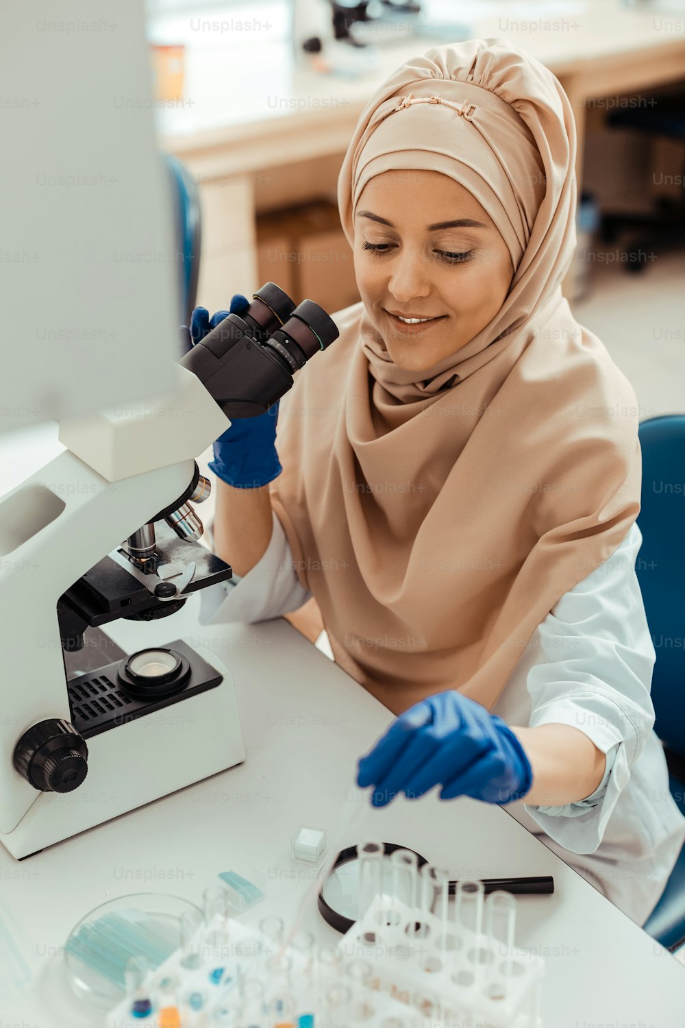 プロの女性科学者。試験管を取っている間の陽気な素敵なイスラム教徒の女性の上面図