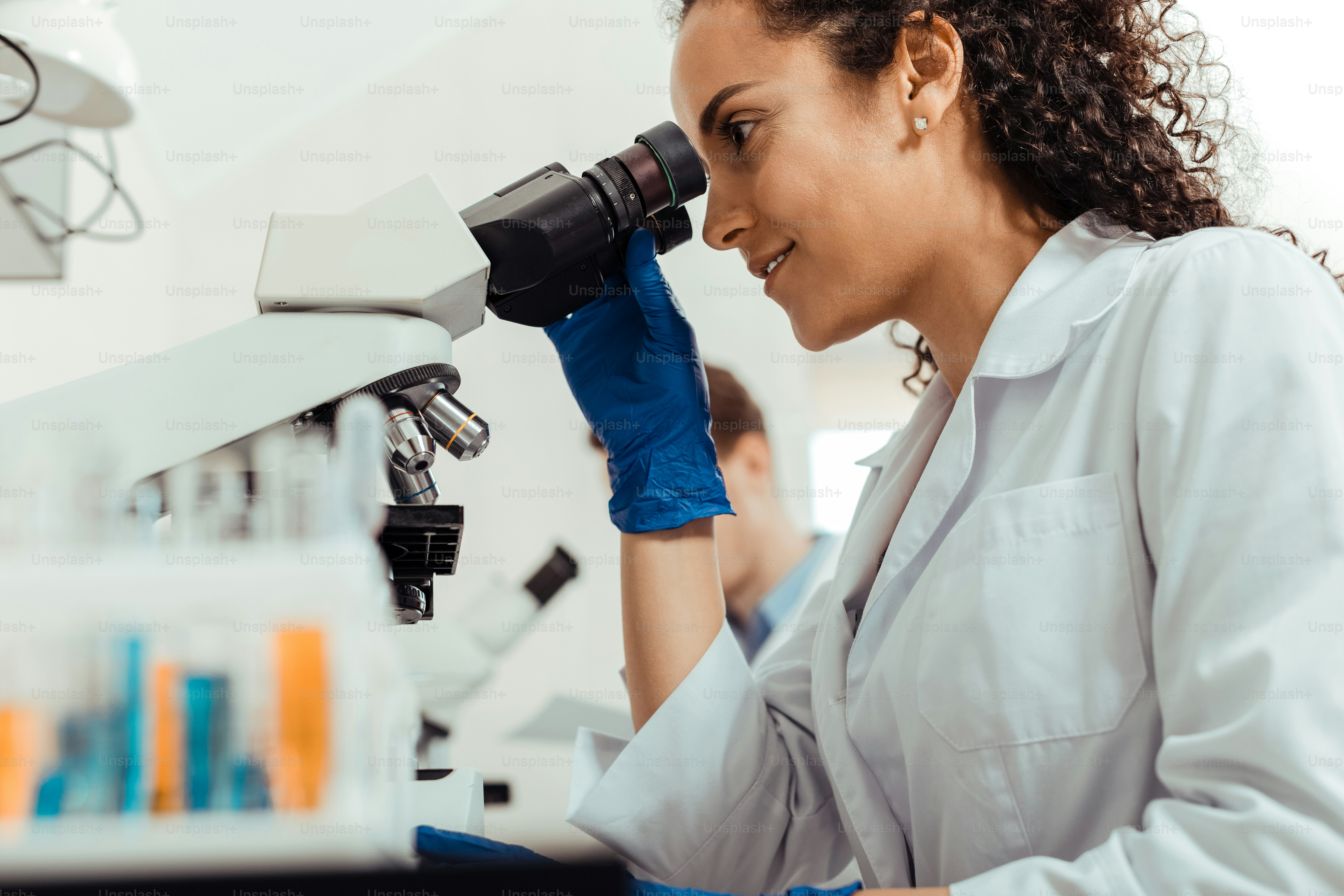 Well equipped laboratory. Joyful smart woman using the microscope while focusing on her work