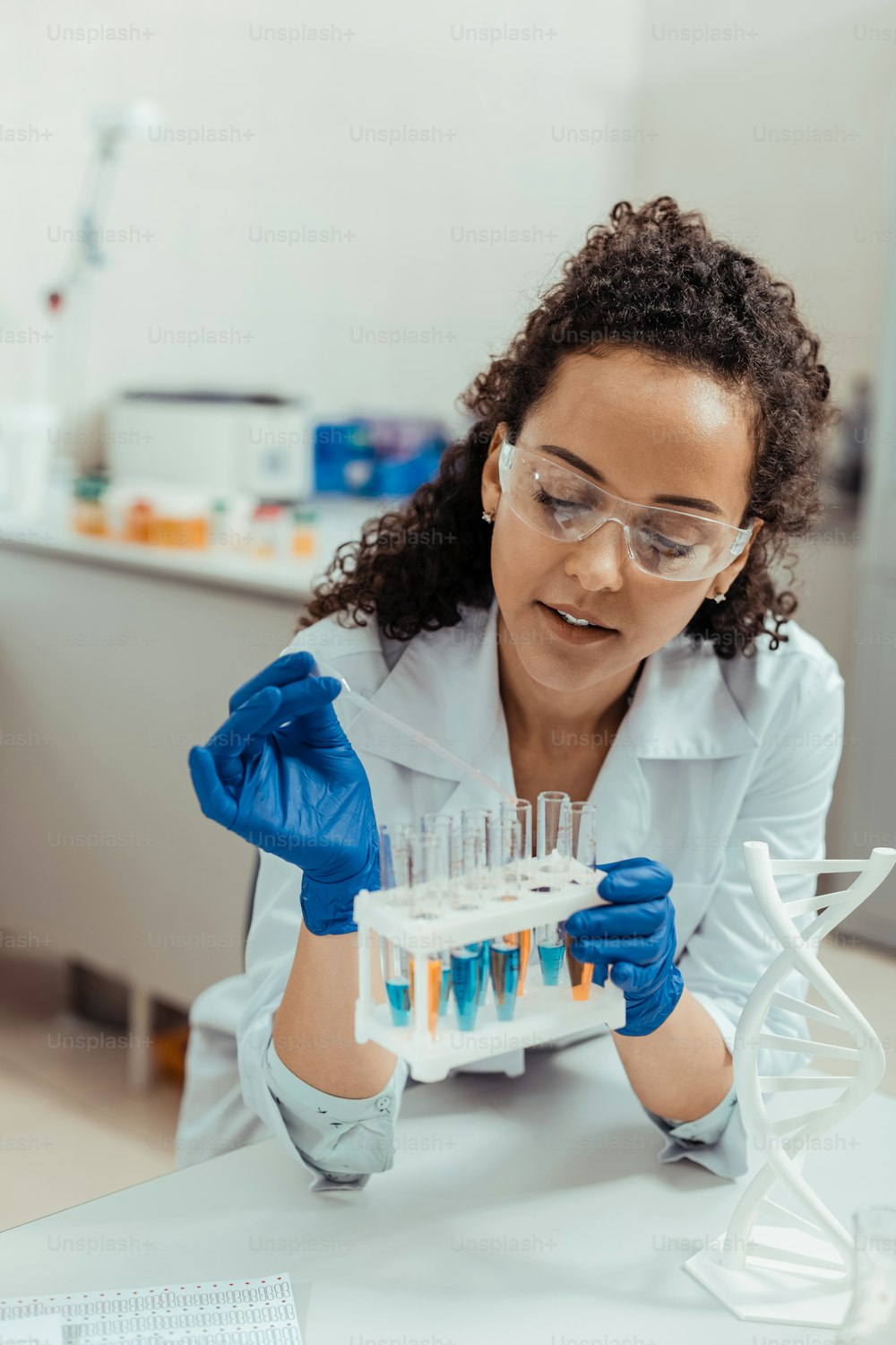 Científica profesional. Buena mujer joven sosteniendo un estante de tubos de ensayo mientras trabaja en el laboratorio