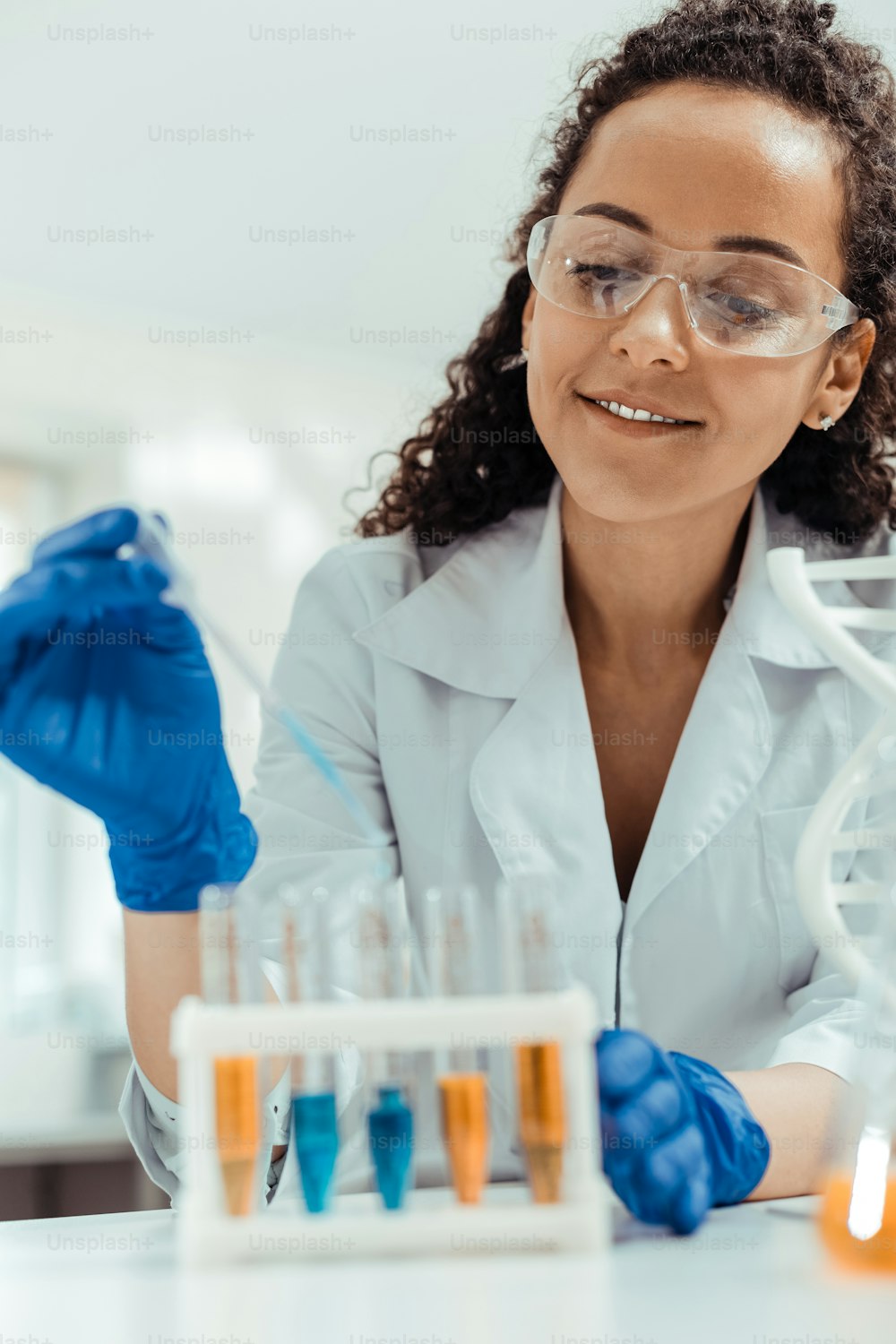 Great mood. Positive young woman looking at the test tubes while enjoying her job in the lab