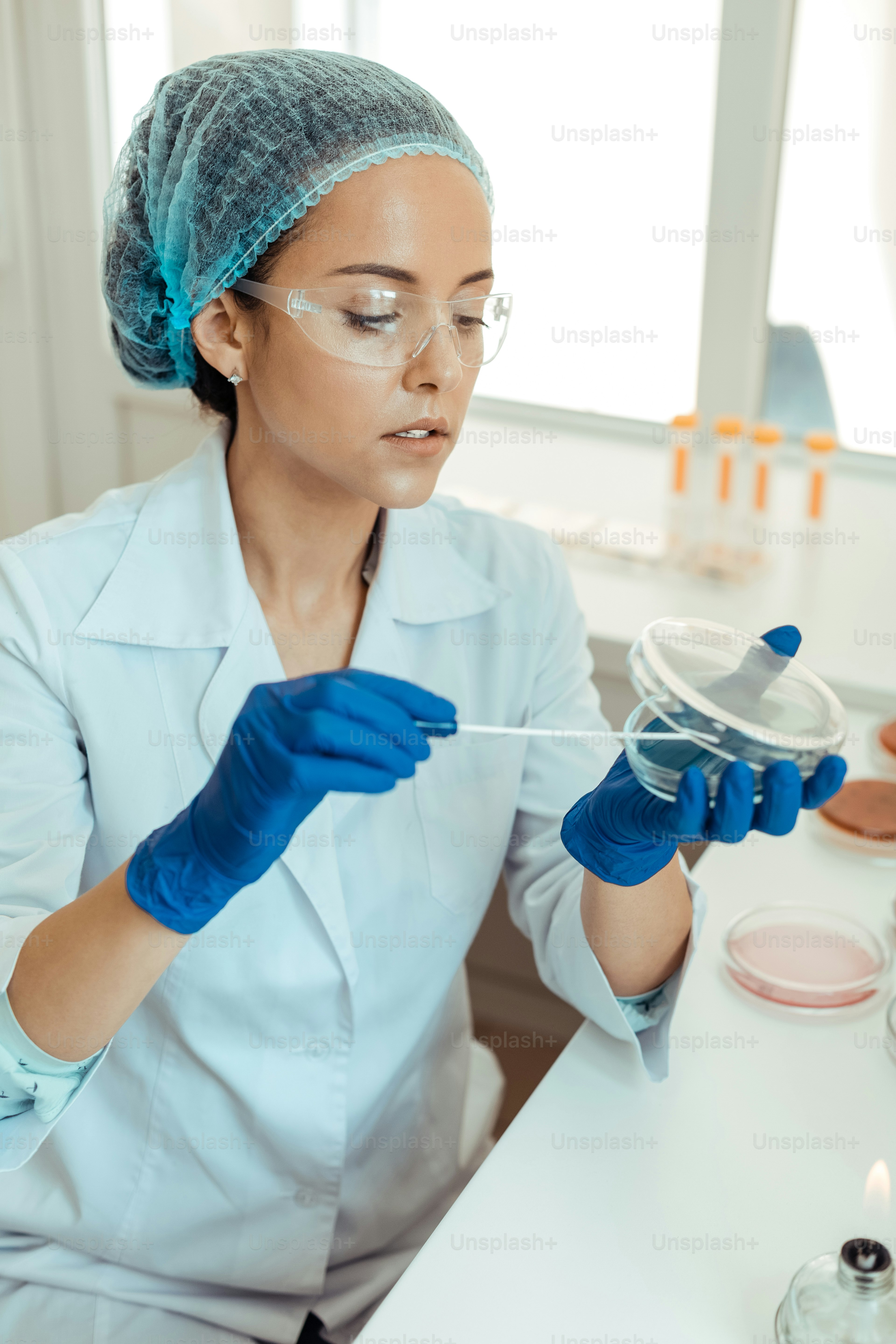 Scientific equipment. Nice thoughtful woman holding a petri dish while looking into it