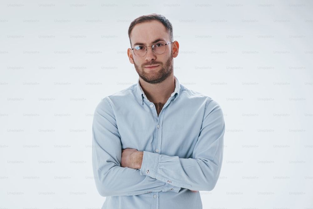 Smart person in eyewear. Man in official clothes stands against white background in the studio.