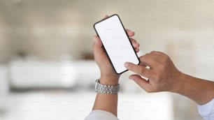 Cropped shot of man holding white screen mobile phone in cafe