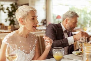 Bride eating salad. Beautiful aged bride eating salad while celebrating wedding with her handsome husband