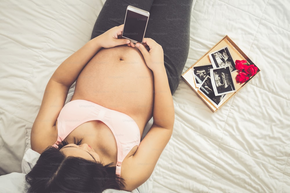 임신한 여자는 아이를 돌보며 집에서 행복을 느낀다. 임신한 뱃속에 아기를 안고 있는 젊은 임산부. 출산 산전 관리 및 여성 임신 개념.