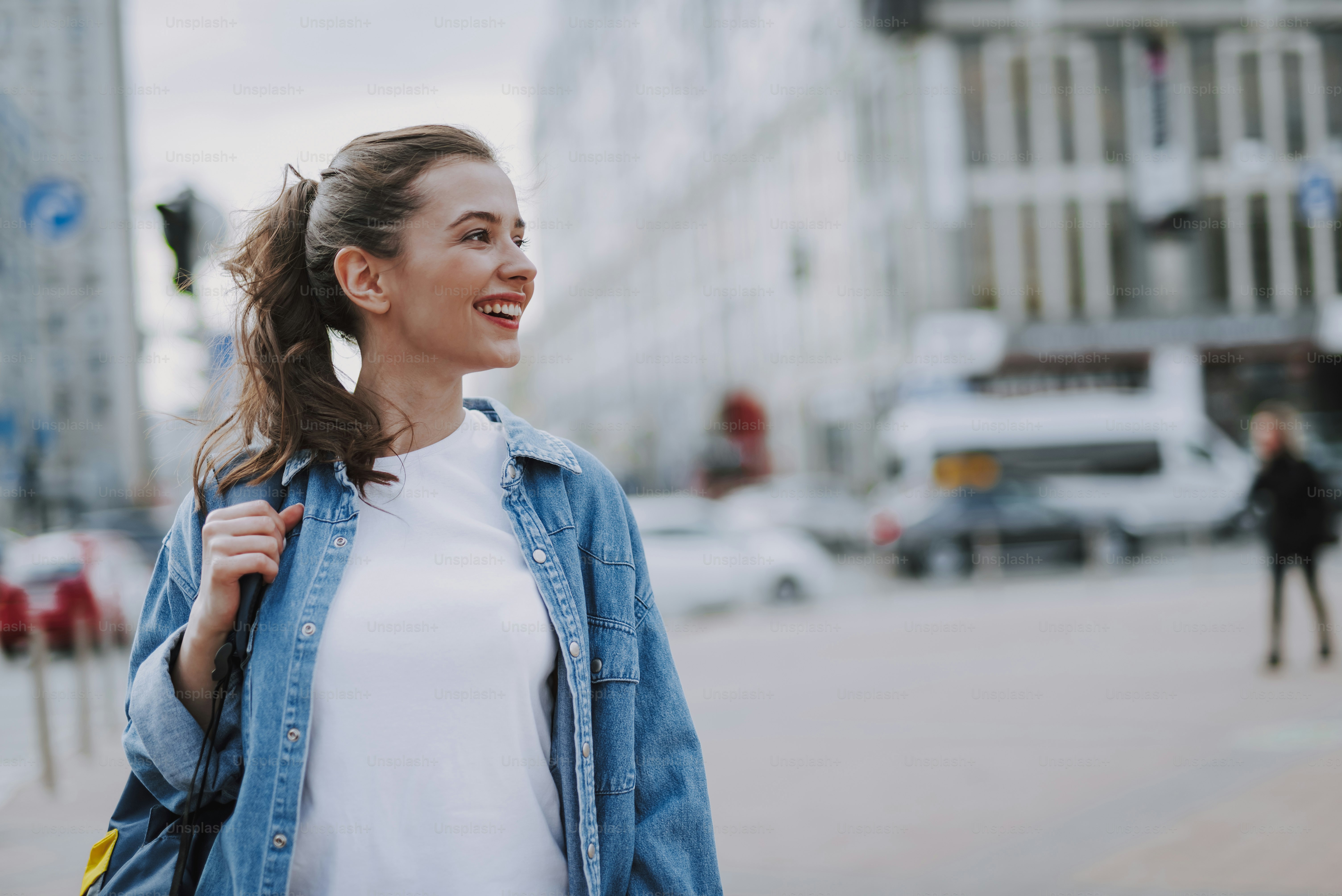 Concept de style de vie urbain. Portrait de visage latéral de la taille d’une jeune jolie dame joyeuse regardant de côté tout en se promenant dans la ville. Copier l’espace à droite
