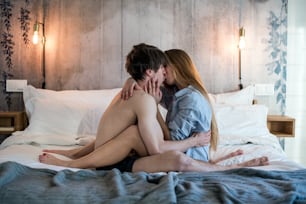 Leidenschaftliches glückliches junges Paar in einem intimen Moment, der zu Hause im Bett sitzt