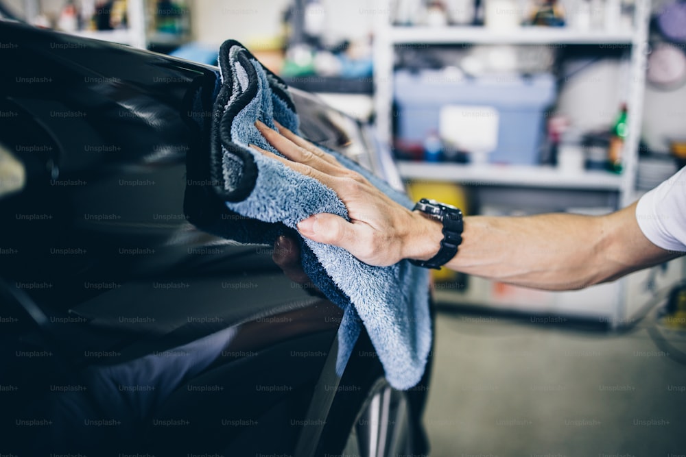 A man cleaning car with microfiber cloth, car detailing (or valeting) concept. Selective focus.