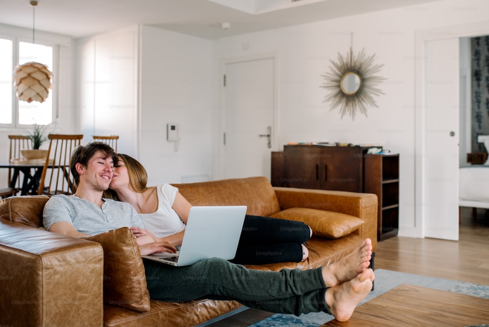 Young couple on the computer on comfortable couch at home