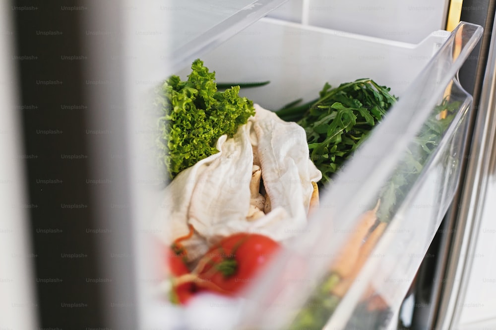 Zero Waste Lebensmittel im Kühlschrank. Frisches Gemüse in geöffneter Schublade im Kühlschrank. Plastikfreie Karotten, Tomaten, Pilze, Rettich, Salat, Rucola, Zero-Waste-Einkaufskonzept. Vegetarische Ernährung