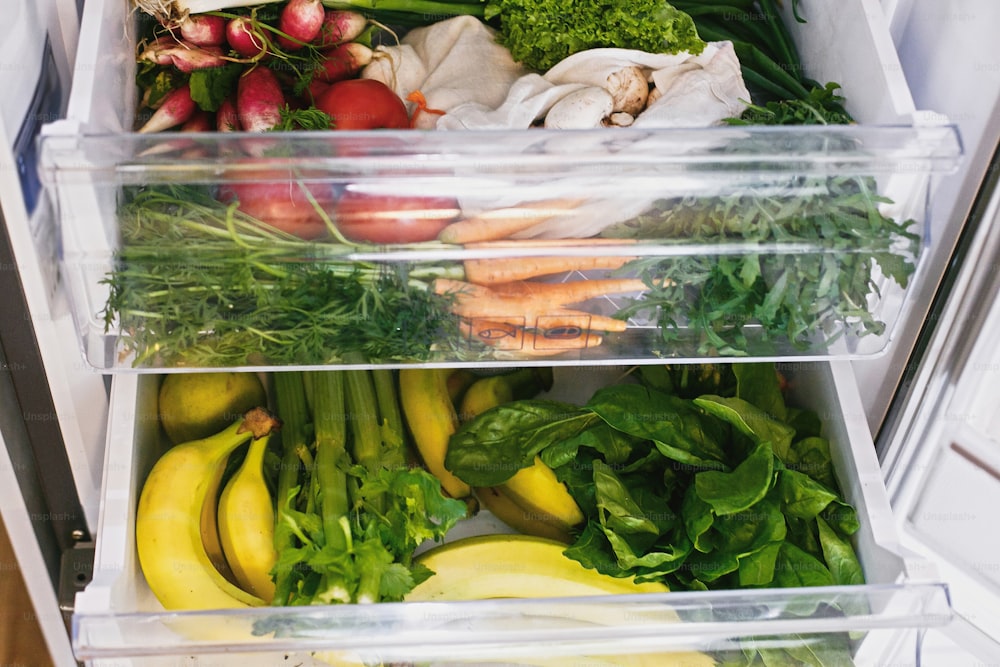 Fresh grocery delivery. Plastic free carrots,tomatoes, mushrooms,bananas,salad, spinach, celery, apples in fridge. Zero waste shopping. Fresh vegetables in opened drawer in refrigerator. Vegan