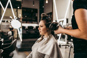 Beautiful brunette woman with long hair at the beauty salon getting a hair blowing. Hair salon styling concept.