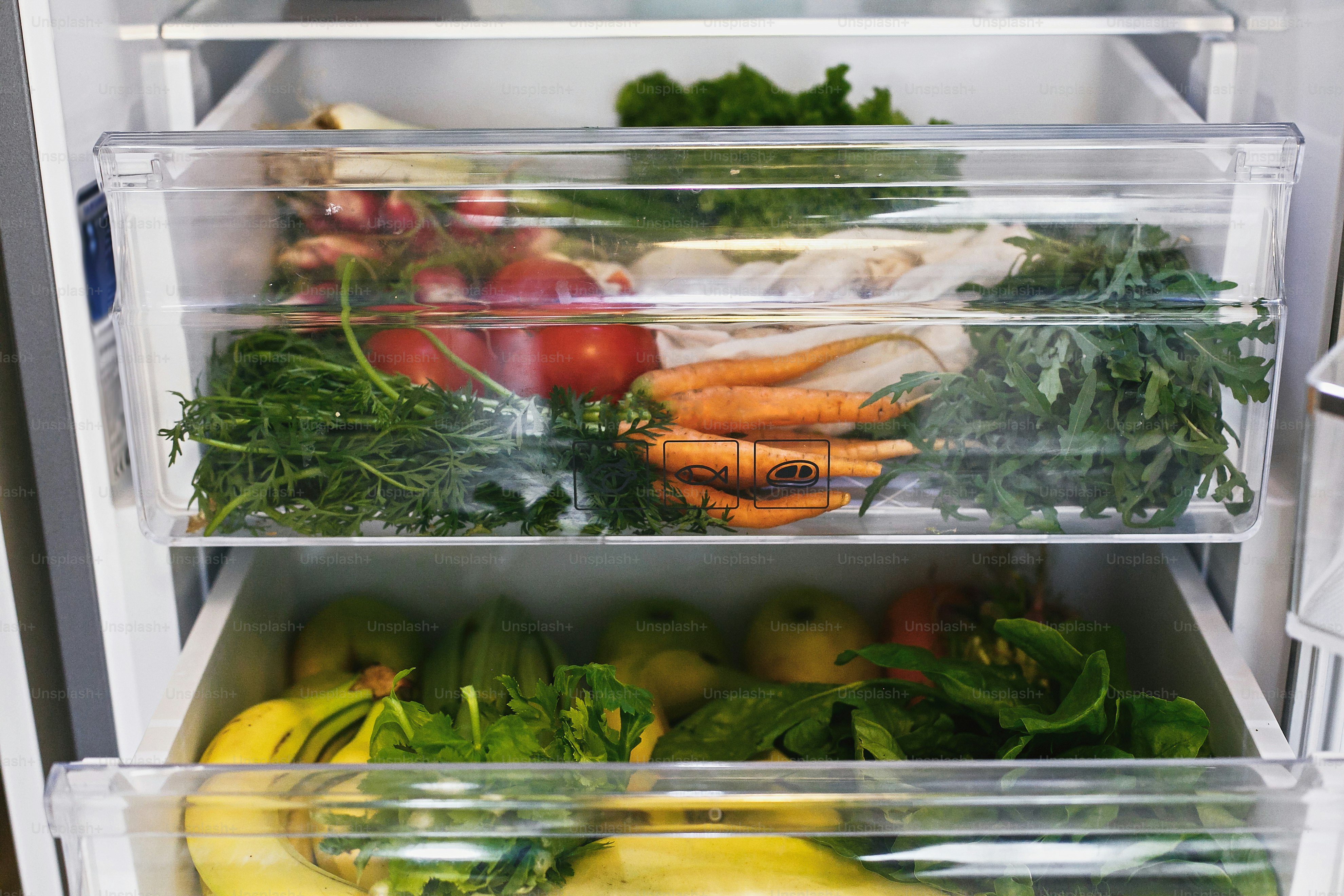 Fresh vegetables and fruit stored in clear plastic refrigerator drawers