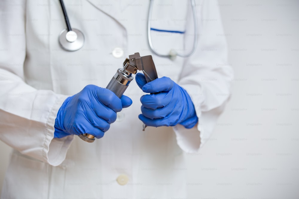 Medico della mano che tiene il laringoscopio, isolato su sfondo bianco, spazio di copia.