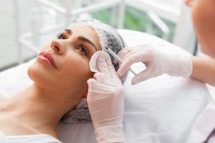 Cosmetology treatment. Close up of a syringe in female hands during the injection in the forehead