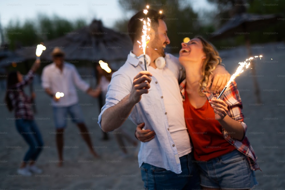 Picture of happy couple holding burning sparkle at beach