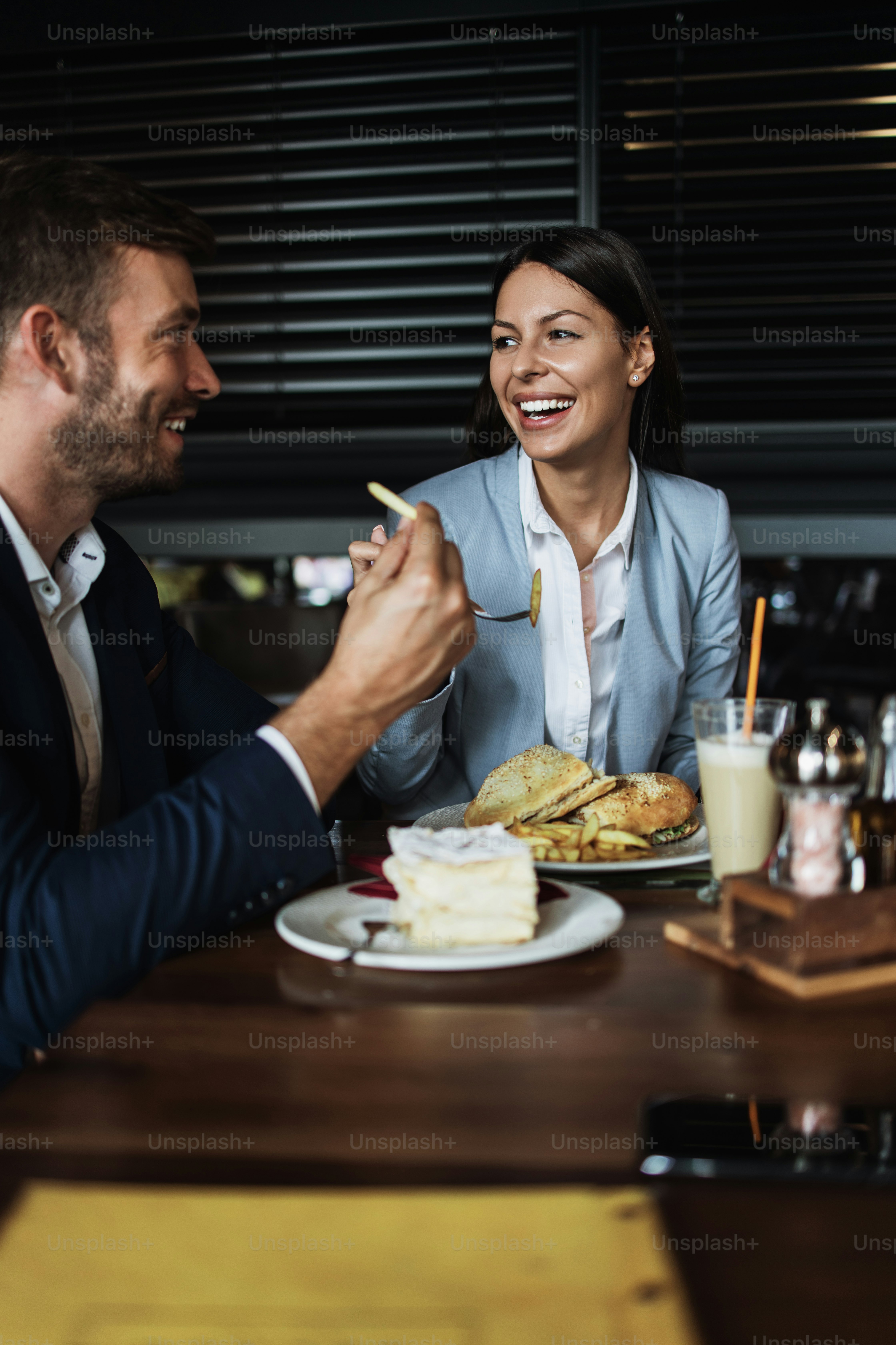 Hombre y mujer de pareja felices sentados en un moderno café, bar o restaurante y bebiendo café.