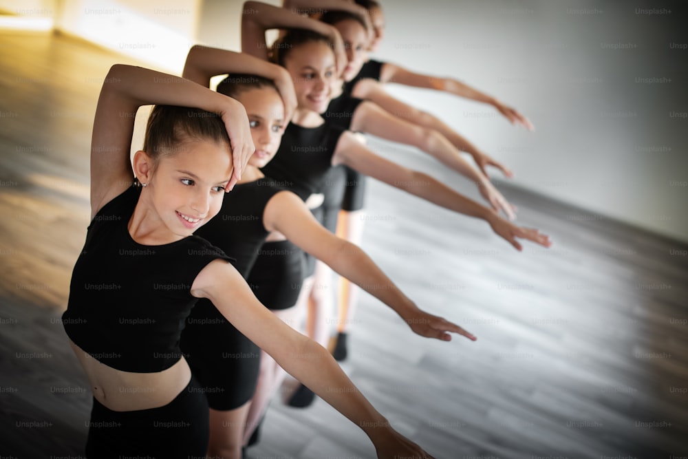 Group of fit children exercising dancing and ballet in studio together