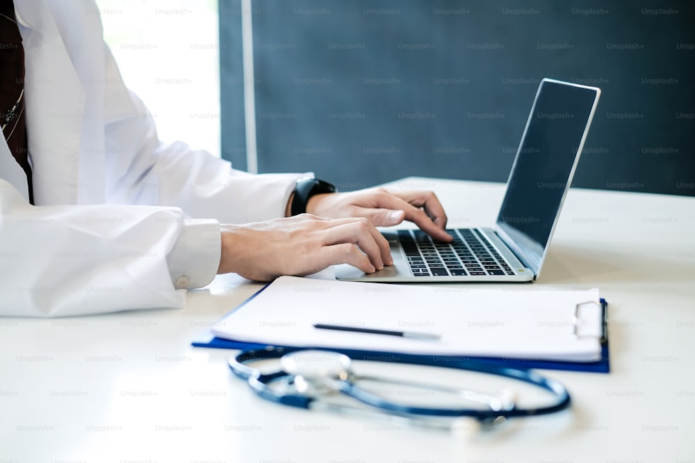 Doctor working with laptop computer and see patient record in document.