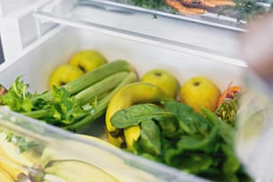 Plastic free bananas,salad, spinach, celery, apples, orange in fridge. Zero waste grocery shopping. Fresh vegetables in opened drawer in refrigerator. Vegetarian diet. Food delivery