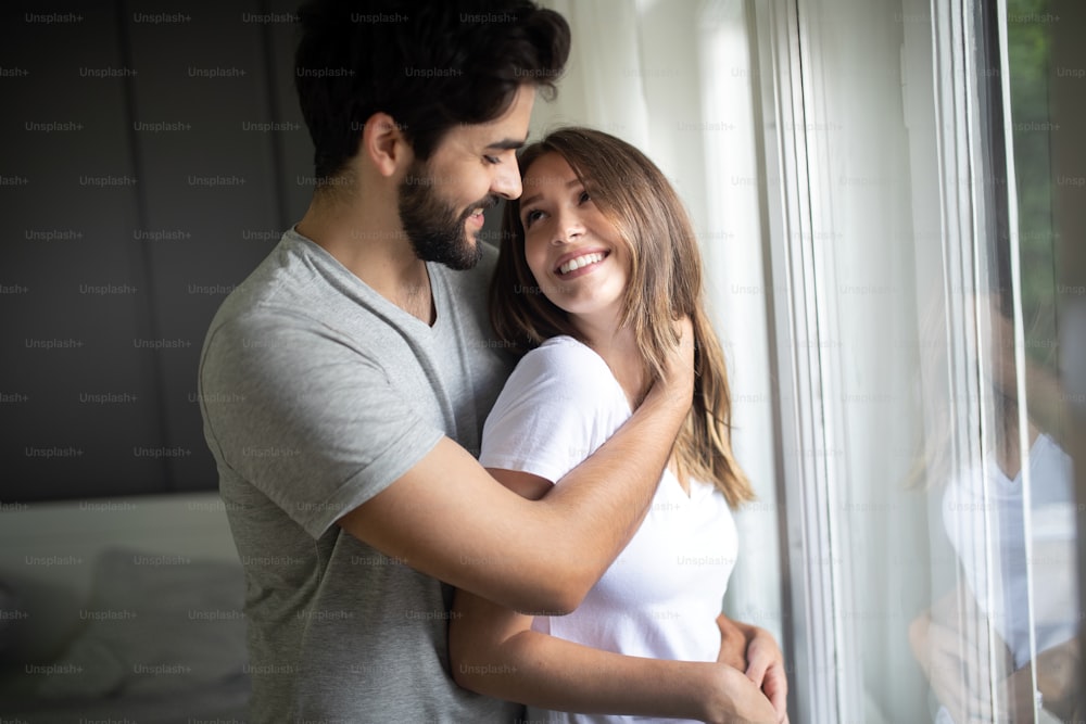 Beautiful couple of young lovers are hugging indoors at home, with love and tenderness