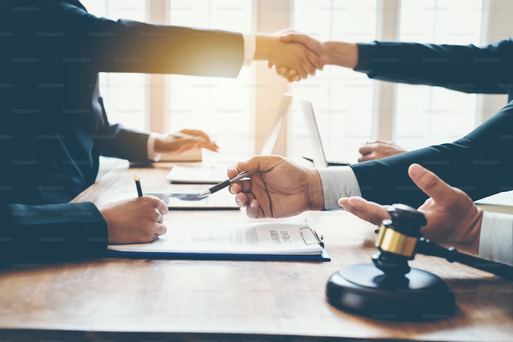 Grupo de empresários apertando as mãos para selar um acordo com seus advogados parceiros ou advogados discutindo um contrato na reunião.