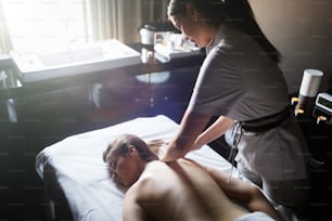 Jeune femme recevant un massage du dos dans un centre de spa. La patiente reçoit un traitement par un thérapeute professionnel.
